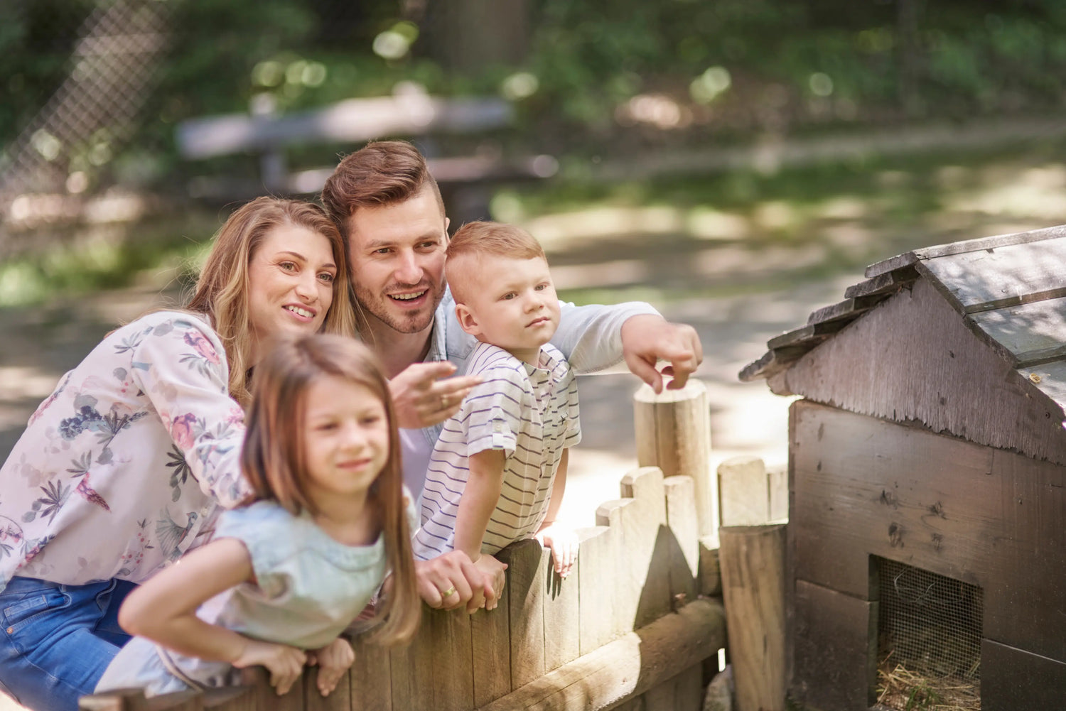 Family of four standing near a wooden structure outdoors
