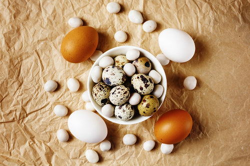 Assorted eggs including quail eggs in a bowl on a brown paper background